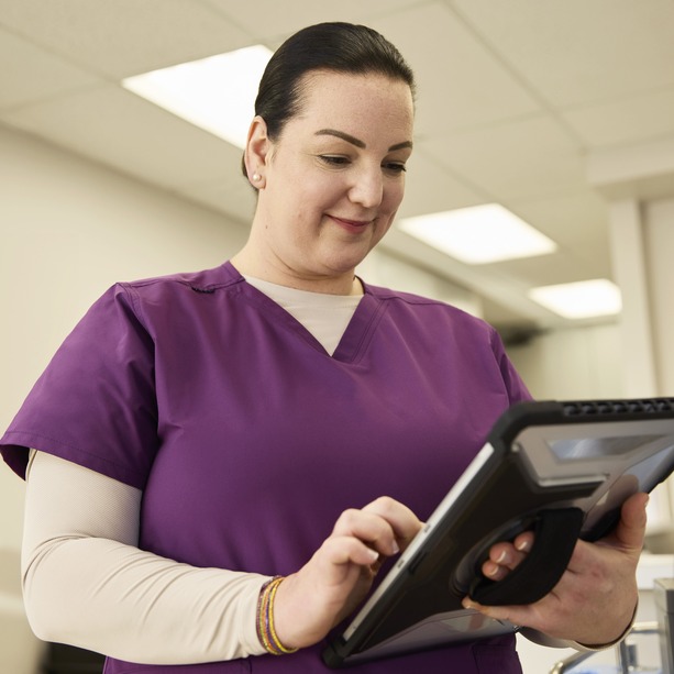 INVIVA nurse smiling while browsing through an iPad.