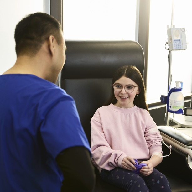 Pediatric patient sitting in treatment chair smiling at nurse sitting infront of her.